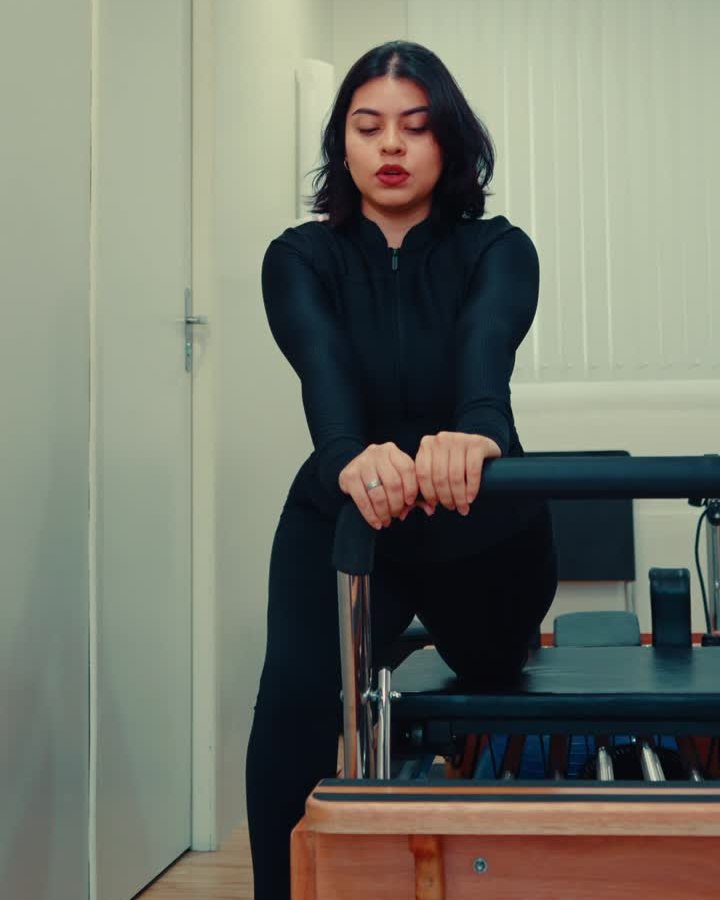Paciente de pilates do IAAM, de roupa preta, num aparelho de pilates